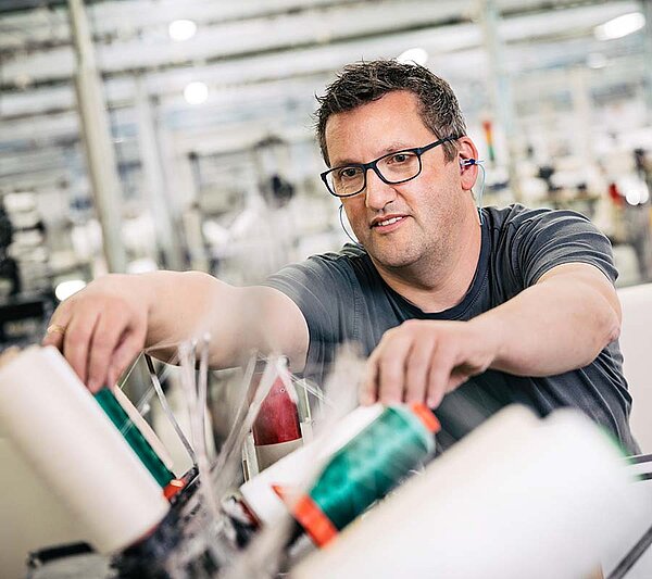 Mitarbeiter arbeitet an einer Maschine zur Ausrüstung und Veredelung von Textilien