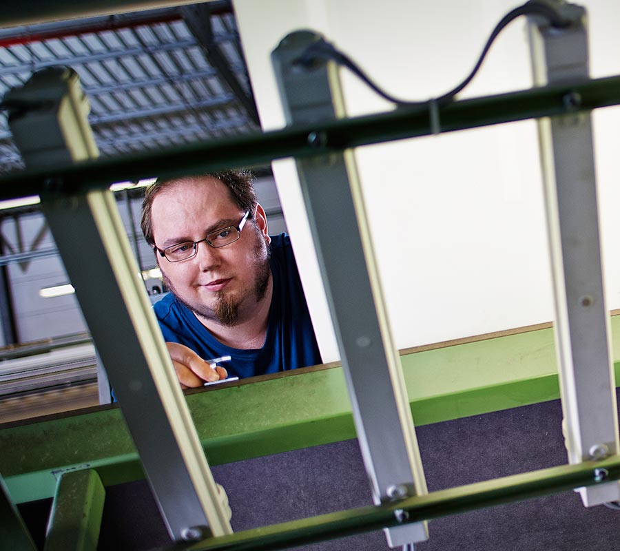 Mitarbeiter kontrolliert eine Textilmaschine in der Velener Produktion